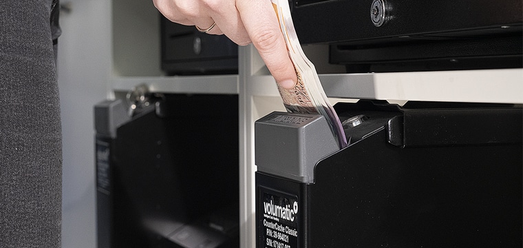 Cash handling best practices image Woman feeding cash into a Volumatic CounterCache Classic device