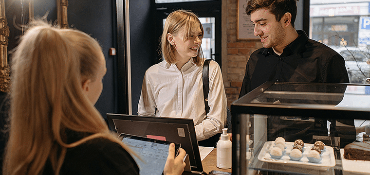 Customers and shop assistant at small retailer